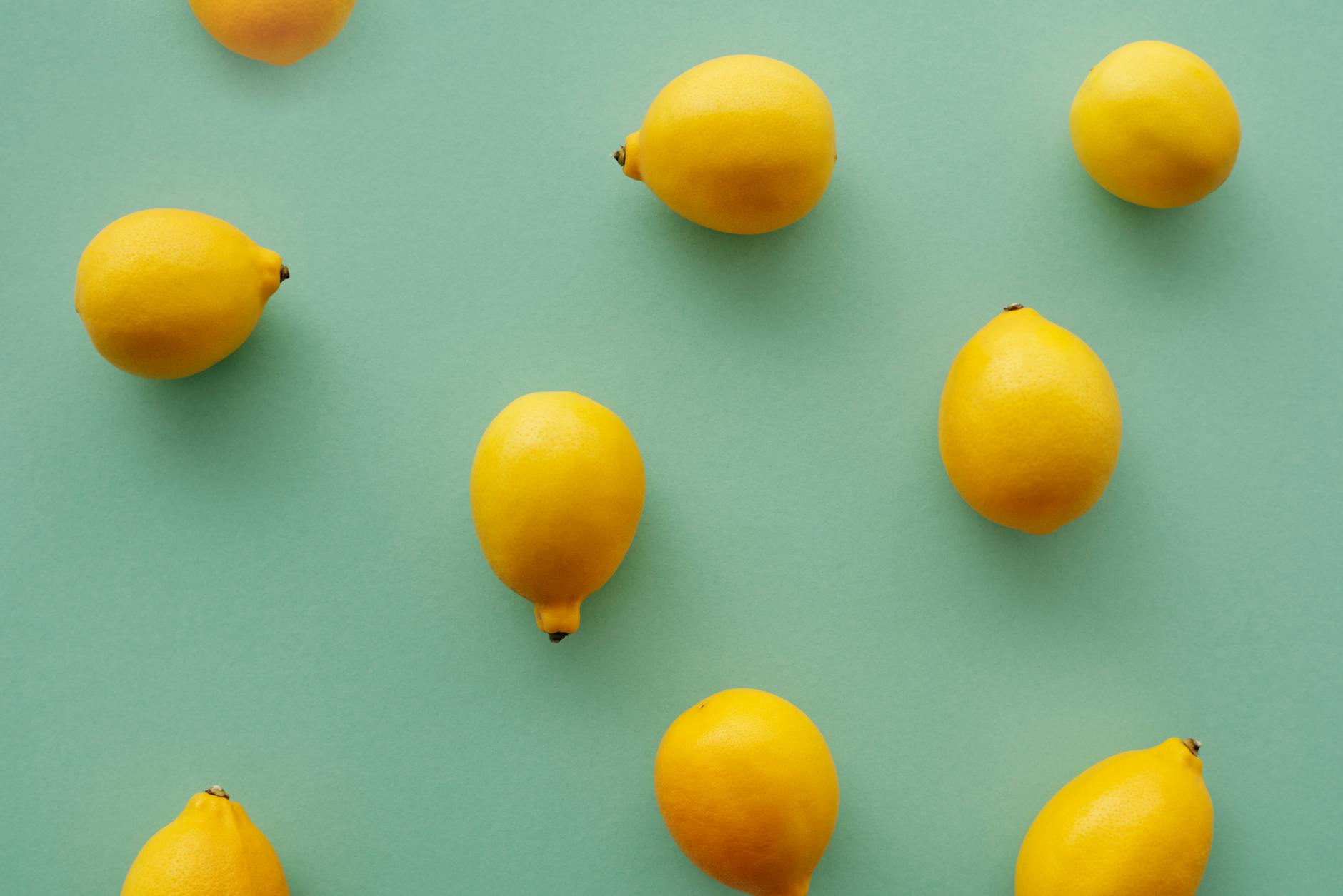 Bright yellow lemons arranged on a pastel green background, symbolizing fresh starts and gentle pleasure.