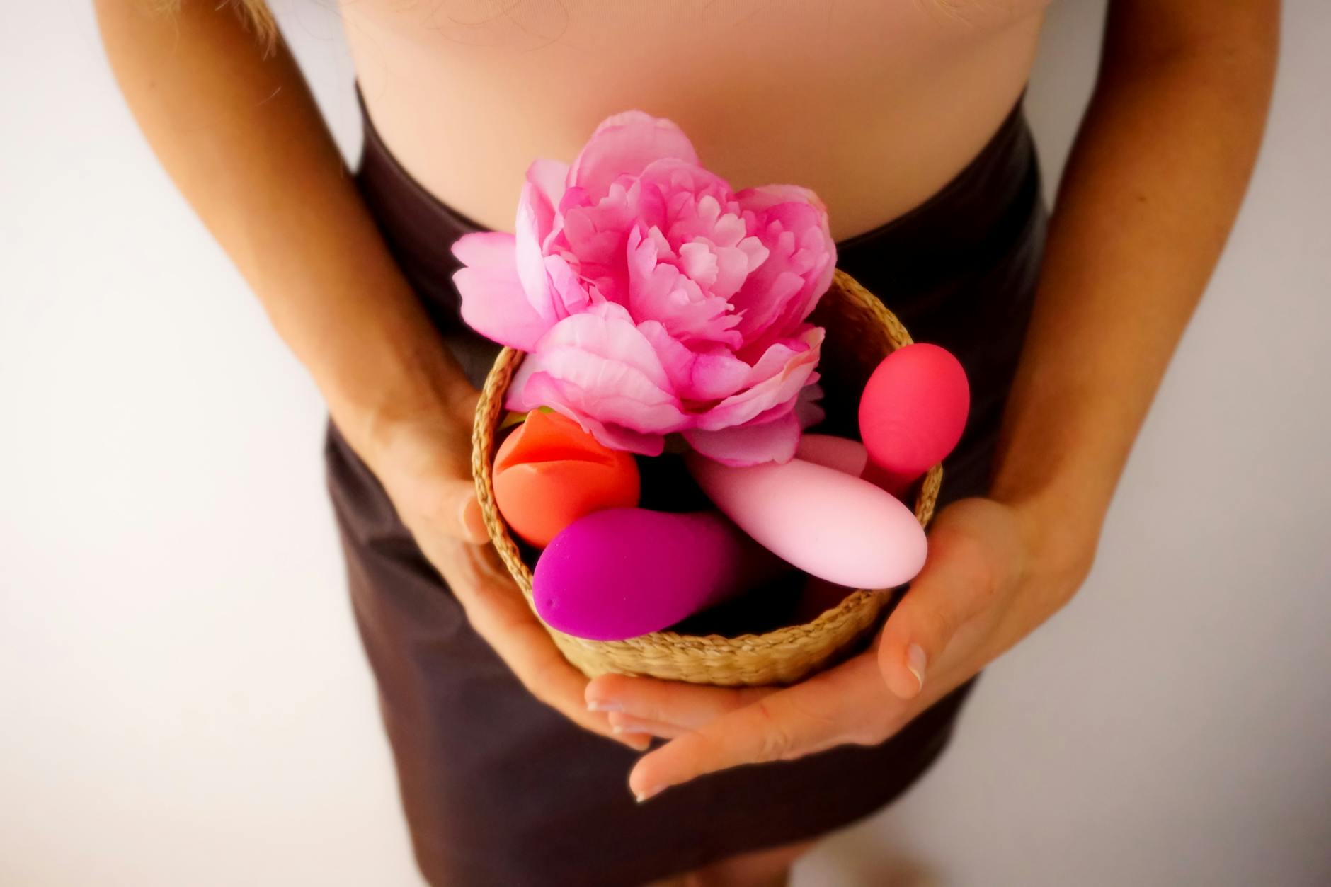 A basket of colorful vibrators and toys with flowers, representing exploring new pleasure tools